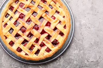 Tasty cherry pie on grey textured table, top view