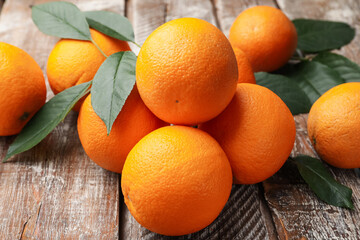 Fresh oranges and leaves on wooden table, closeup