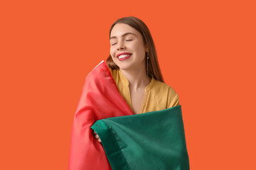Happy young woman with Mexican flag on orange background