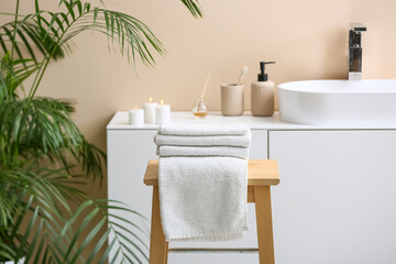 Stack of clean soft towels on wooden table in interior of modern bathroom