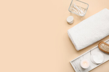 Composition with rolled soft towel, stone tray, cotton pads and candle on beige background