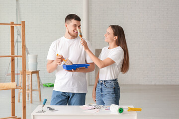 Young couple with brushes doing repair in their new house
