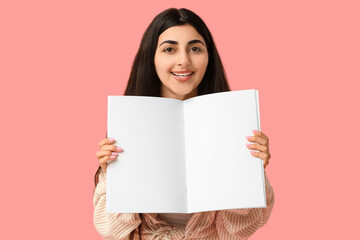 Beautiful young happy woman with open blank magazine on pink background