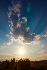 Sunset sun rays penetrate clouds on blue sky, cloudscape