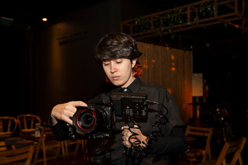 Primer plano de joven con cámara en mano y monitor digital filmando secuencia en fiesta