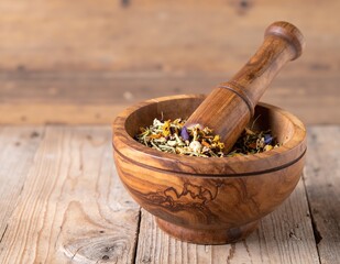A rustic wooden mortar filled with an array of colorful dried flowers, showcasing delicate petals and textures, set against a soft, neutral background.