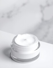 A sleek white jar of luxurious cream sits elegantly on a polished marble surface, reflecting soft light and showcasing its smooth, minimalist design.