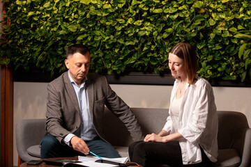Two business colleagues discuss documents intently on a modern sofa. Professional teamwork,...