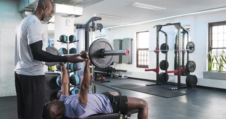 On command trainee pressing loaded barbell under trainer spotting at gym bench press station - Powered by Adobe