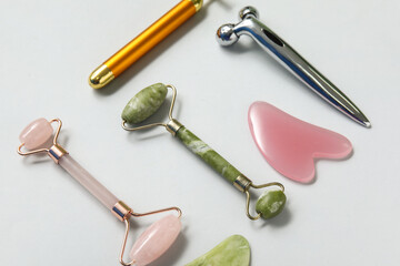 Different face massage rollers and gua sha on grey background