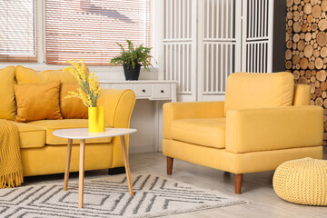 Interior of stylish living room with yellow sofa, coffee table and folding screen