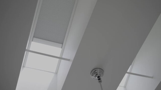 This close up video shows two large skylight as their blinds open up to light up the interior of a home. 