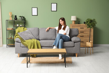 Beautiful young woman resting on cozy sofa in living room