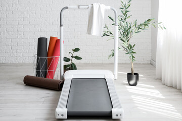 Treadmill with towel and fitness mats in light room