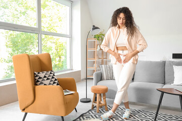 Young African-American woman suffering from menstrual cramps at home