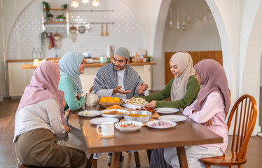 Muslim big family sharing traditional meal together around dining table wearing hijabs and kufi in cultural love, ramadan iftar celebration, eid al-fitr festive, halal meal gathering food culture