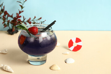Glass of tasty cocktail with strawberry and shells on colorful background