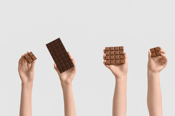 Female hands with different sweet chocolate on white background