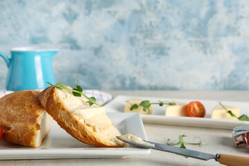 Plates with fresh bread, triangles of tasty processed cheese and micro green on light table
