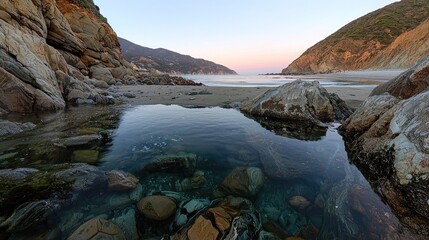 Peaceful coastal cove at dawn with clear, shallow water reflecting the surrounding landscape.
