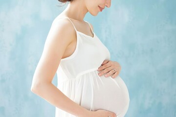 Close-Up Profile of Pregnant Woman Gently Holding Her Belly Against a Soft Blue Background