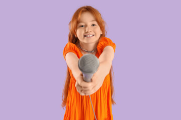 Teenage redhead girl with microphone on lilac background
