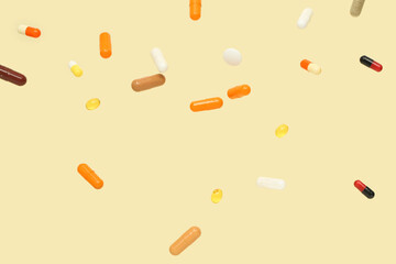 Flying colorful pills on yellow background