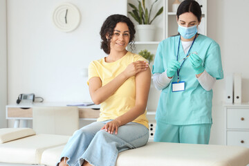Young African-American woman getting vaccine from doctor in clinic