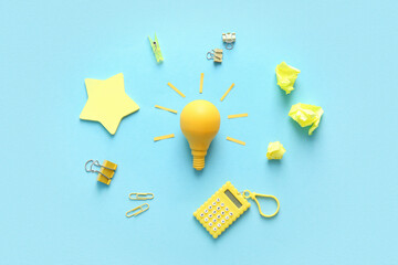 Yellow light bulb with stationery on blue background