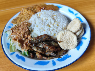 Nasi pecel or sego pecel is a typical Javanese Indonesian dish served with pecel sauce, which can be added with vegetables, peyek, fish, crackers, tempeh and other side dishes.