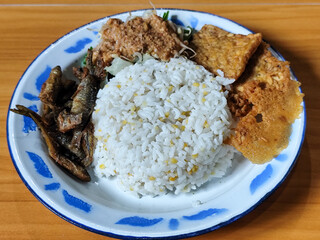 Nasi pecel or sego pecel is a typical Javanese Indonesian dish served with pecel sauce, which can be added with vegetables, peyek, fish, crackers, tempeh and other side dishes.
