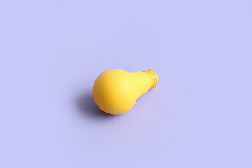 Yellow light bulb on lilac background
