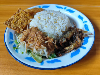 Nasi pecel or sego pecel is a typical Javanese Indonesian dish served with pecel sauce, which can be added with vegetables, peyek, fish, crackers, tempeh and other side dishes.