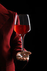 Young woman with glass of red wine on black background