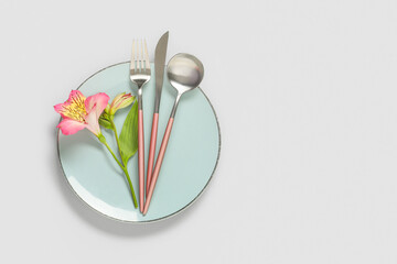 Table setting with plate, cutlery and alstroemeria flower on white background