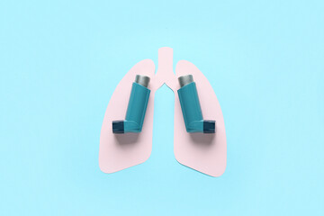 Asthma inhalers with paper lungs on blue background