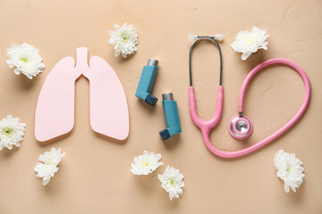 Asthma inhalers with stethoscope, paper lungs and chrysanthemum flowers on beige grunge background