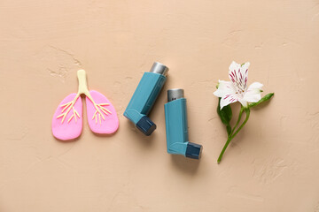 Asthma inhalers with lungs figurine and alstroemeria flower on beige grunge background