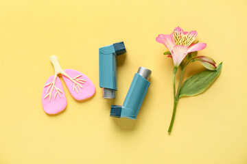 Asthma inhalers with lungs figurine and alstroemeria flower on yellow grunge background