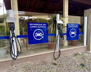 Imagem de ponto de carregamento para veículos elétricos com sinalização em português. Representa mobilidade sustentável e infraestrutura ecológica. Perfeito para questões relacionadas com energia limp
