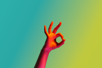 Toned female hand showing OK on color background
