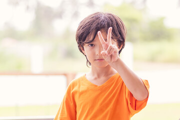 Happy caucasian boy showing victory sign with two fingers.