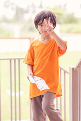 Happy caucasian boy showing victory sign with two fingers.boy with fingers shows peace or victory sign on green nature background.