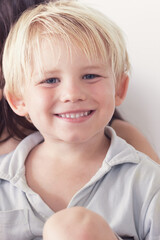 happy small caucasian boy smiling to camera. Portrait of happy kid smiling to camera. A cheerful young boy with blonde hair is smiling broadly showing her teeth on nanture background. Natural emotion.
