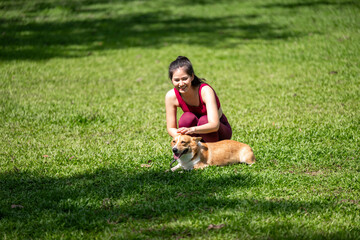 A woman is sitting on the grass with a dog
