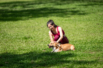 A woman is petting a dog in a park