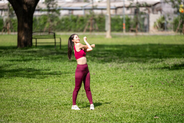 A woman in a red top and red pants is stretching in a park