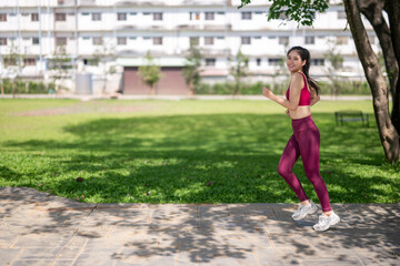 A woman in a red top and black leggings runs in a park