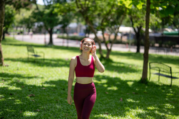A woman is walking in a park wearing a red tank top and red pants
