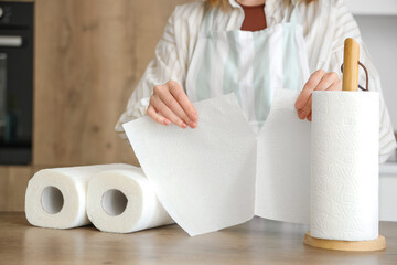 Young woman with rolls of paper towels near table in kitchen, closeup